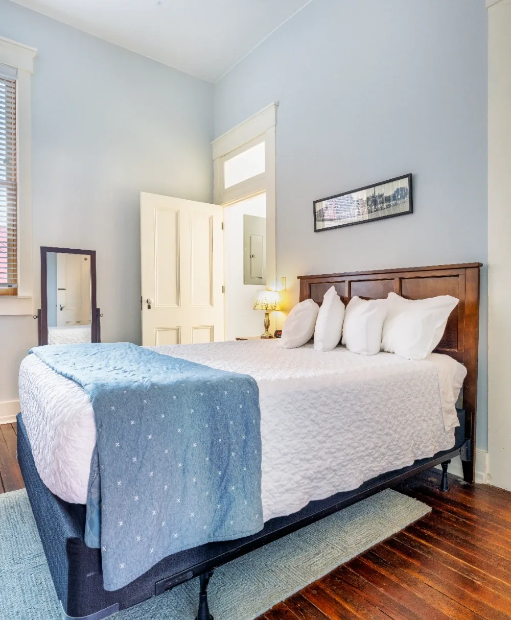 Airy Minimal Bedroom With White Bedding, Natural Light, Wood Headboard, and Blue Throw