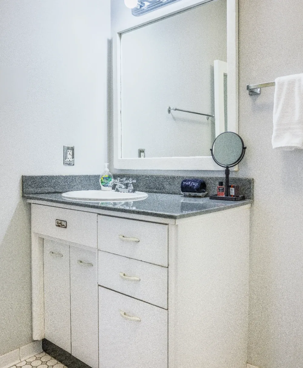 Minimal white bathroom vanity with gray stone countertop, inset sink, and wall mirror