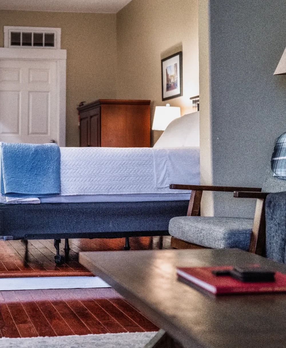 Cozy white bedroom with blue throw, coffee table, and warm light hotel-style comfort