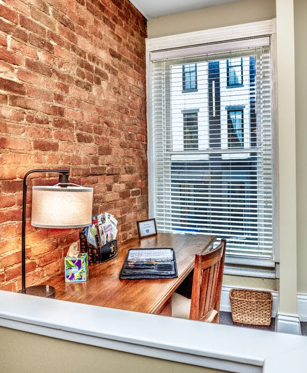 Cozy brick wall home office nook with window light, laptop desk, and woven storage basket