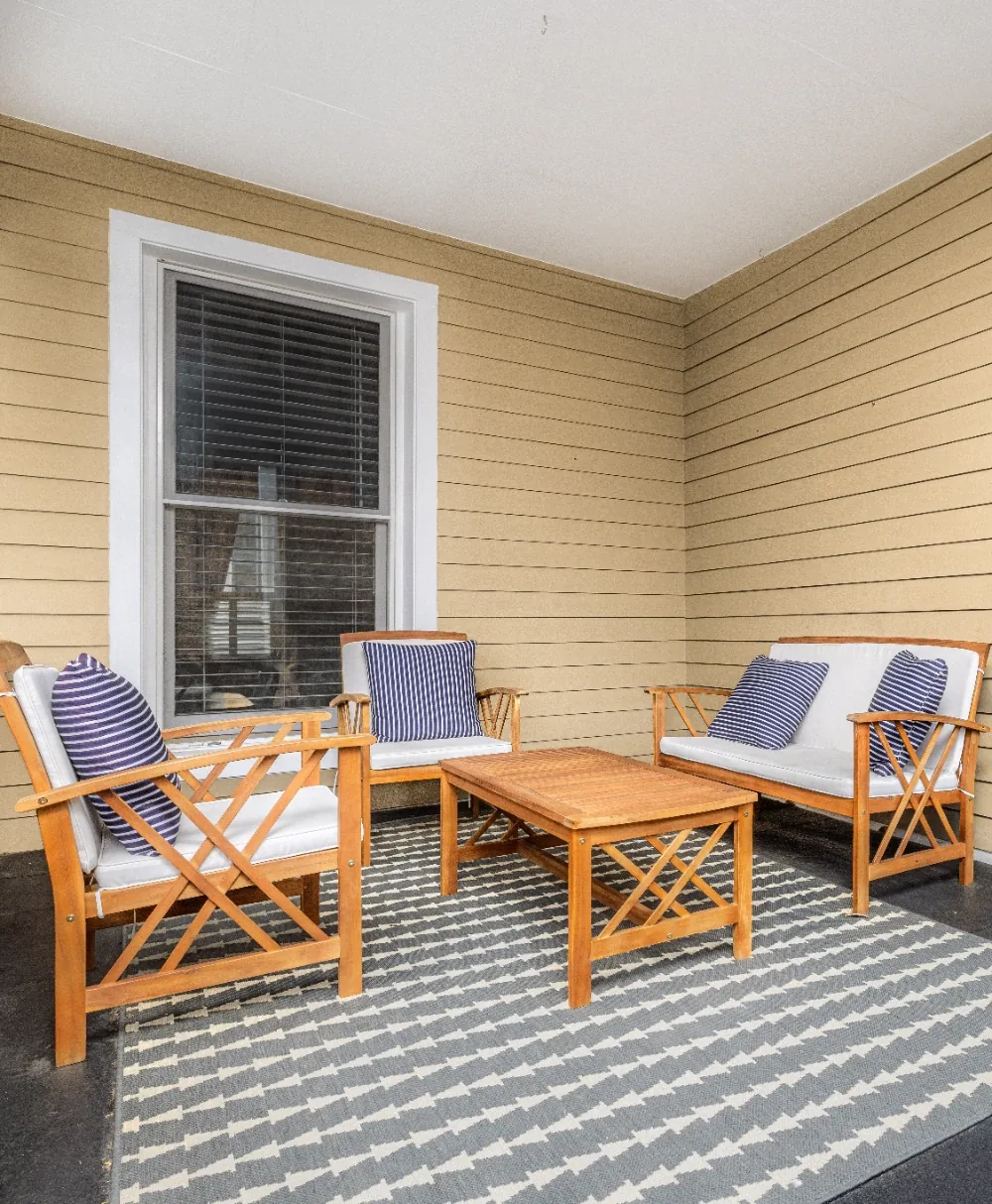 Cozy enclosed porch seating nook with honey wood chairs, navy pillows, and zigzag rug