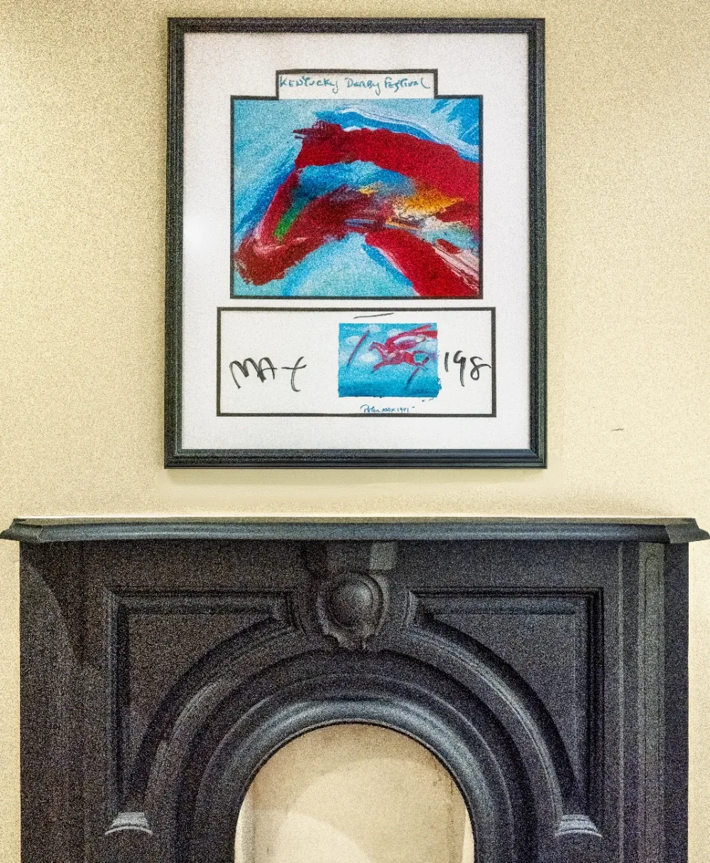 Red and blue abstract painting with double mat above ornate fireplace mantel.
