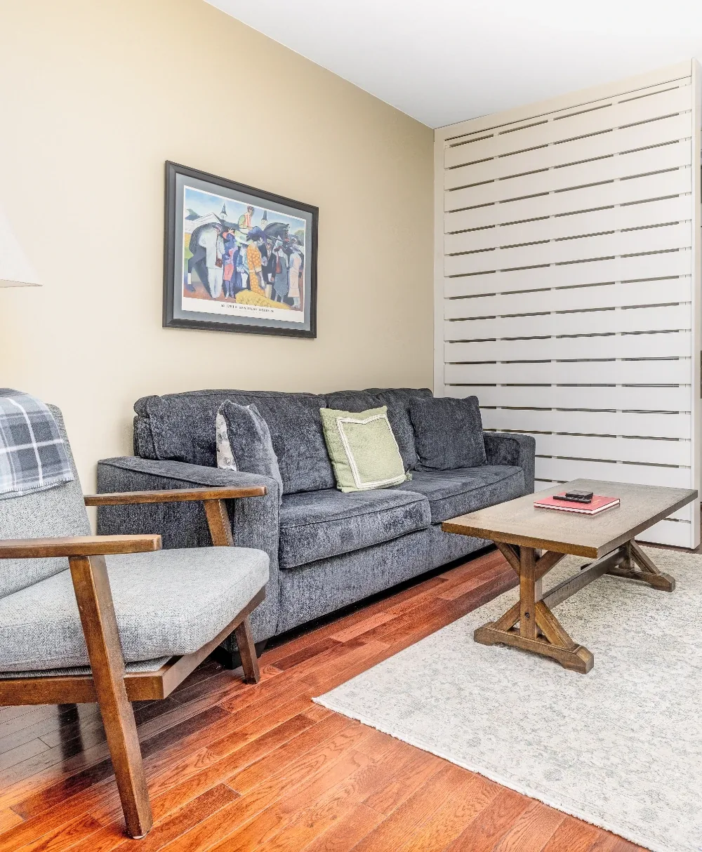 Cozy gray sofa living room with wood coffee table, framed art, and white blinds