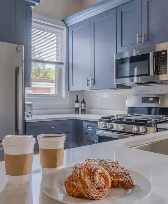 Fresh pastries and takeaway coffee in a bright modern kitchen with blue-gray cabinets