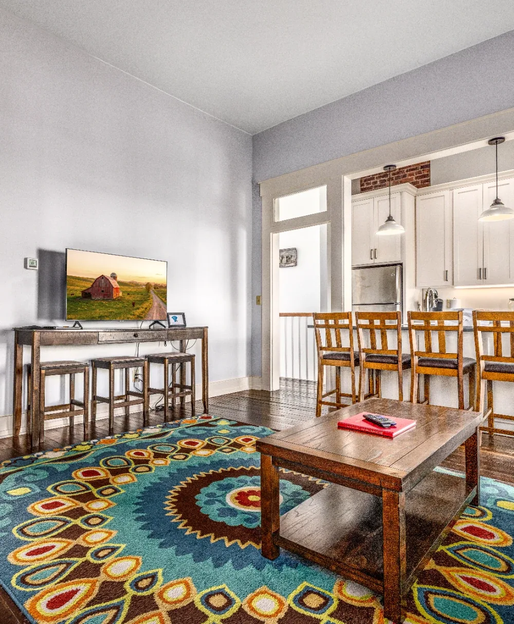 Bright open living room with round patterned rug, wood coffee table, and modern kitchen bar