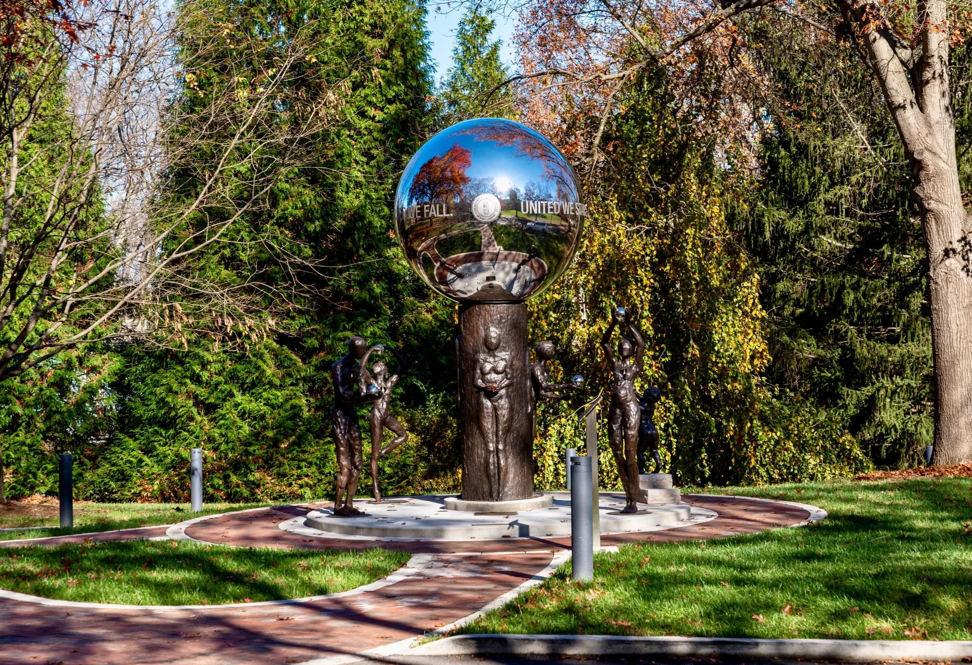 Mirror Sphere Sculpture on Bronze Pedestal in Sunny Park Plaza with Reflective Trees
