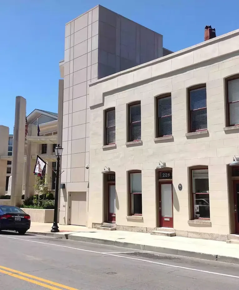Sunny urban street with historic cream facade, mahogany doors, and modern tower building