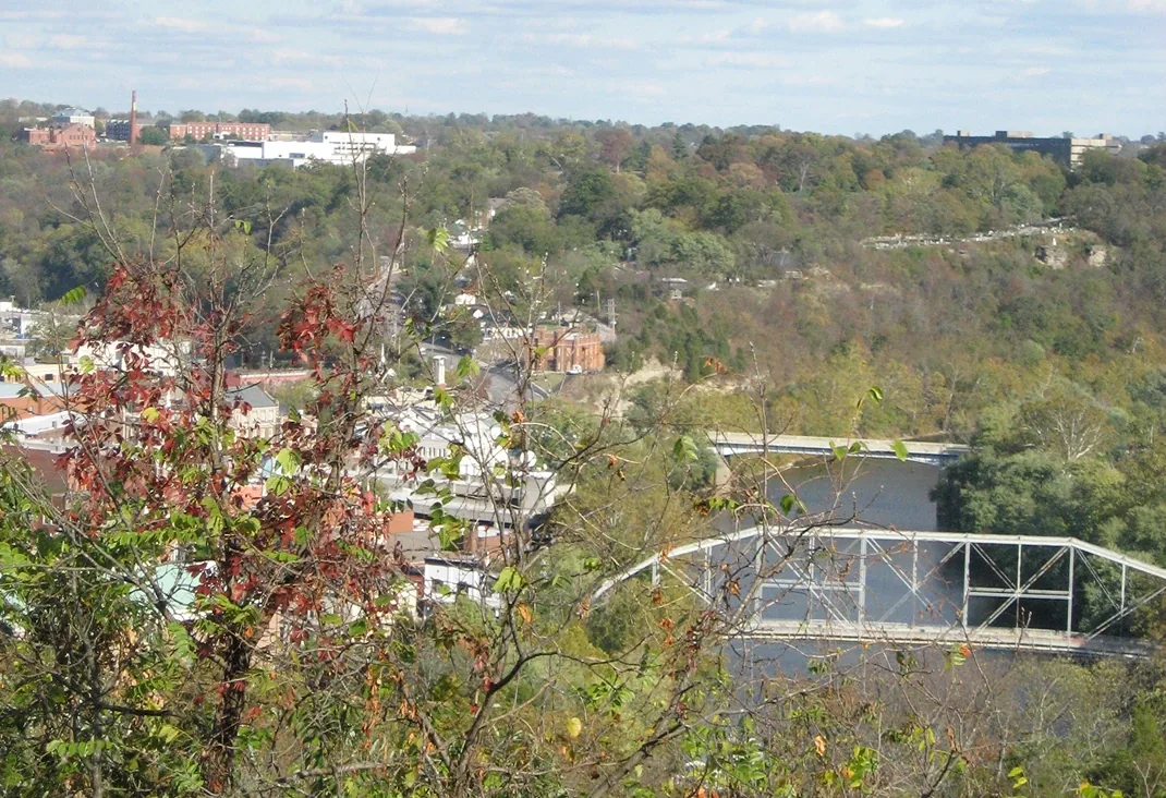 Autumn river valley bridge with truss span, hillside views, and wooded hills in the distance