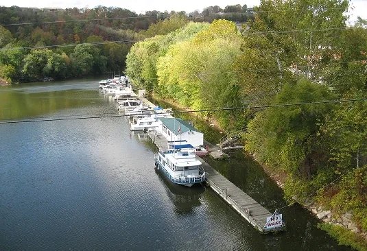 Quiet riverside dock with moored boats and calm water, wooded banks and soft autumn light