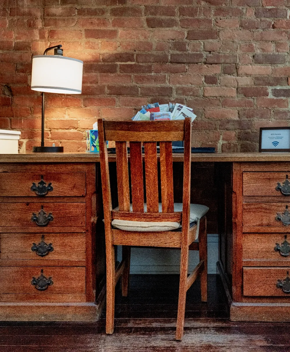 Rustic brick home office nook with warm wooden desk, vintage drawers, and cozy chair under soft light