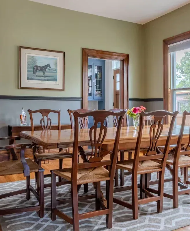 Serene natural light dining room with wooden table, patterned rug, and pink flowers