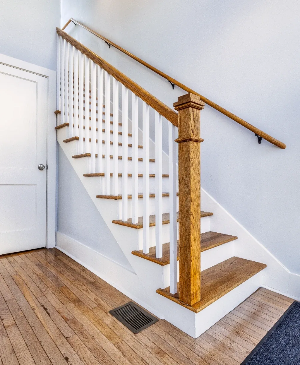 Classic interior staircase with warm wood treads, white trim, and gray-blue walls